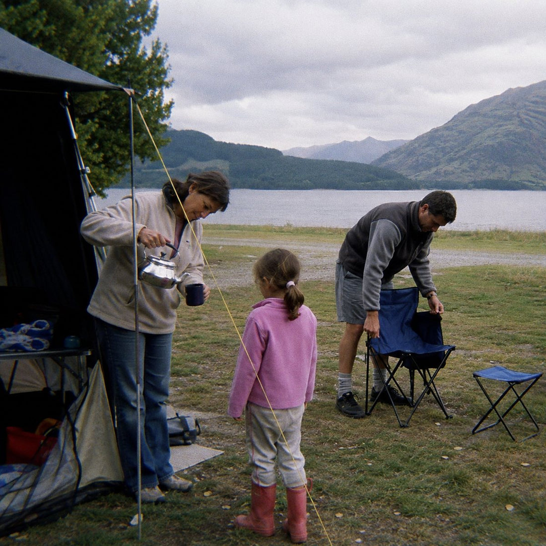 Setting up camp beside a lake on an overcast morning, wide landscape with soft light