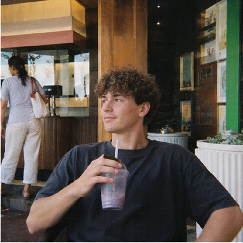 Young man with an iced drink outside a cafe, soft retro digicam style portrait