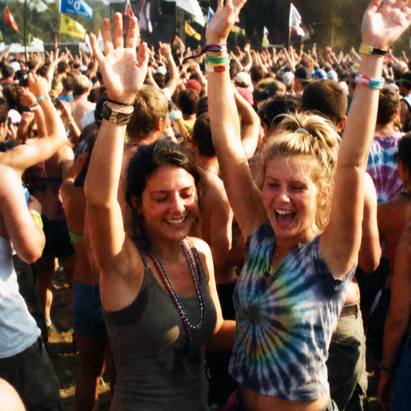 Two women cheering with their hands up in a festival crowd