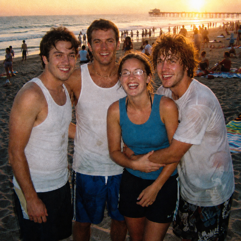 Four friends hugging on the beach near a pier at sunset after a swim