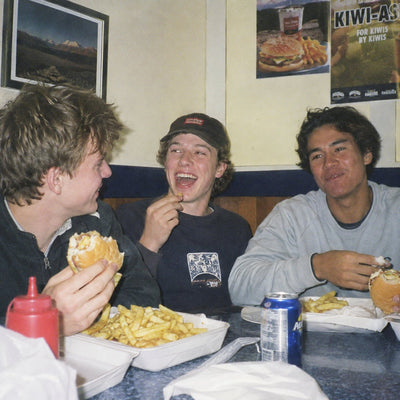Three mates eating burgers and chips in a corner booth