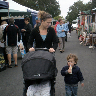 A mum walking the weekend markets with a pram and a toddler